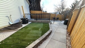 A backyard with artificial grass, a wooden fence, and a concrete pathway. - Luxury-Modern Suite /Cozy CO Vibes /Private Yard (Aurora)