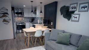 A modern kitchen with a dining area, grey sofa, and decorative wall art. - Luxury-Modern Suite /Cozy CO Vibes /Private Yard (Aurora)