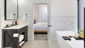 A modern bathroom with a large mirror, a sink with toiletries, a bathtub, and a shower area. - Balsam Lake Lodge (Balsam Lake)