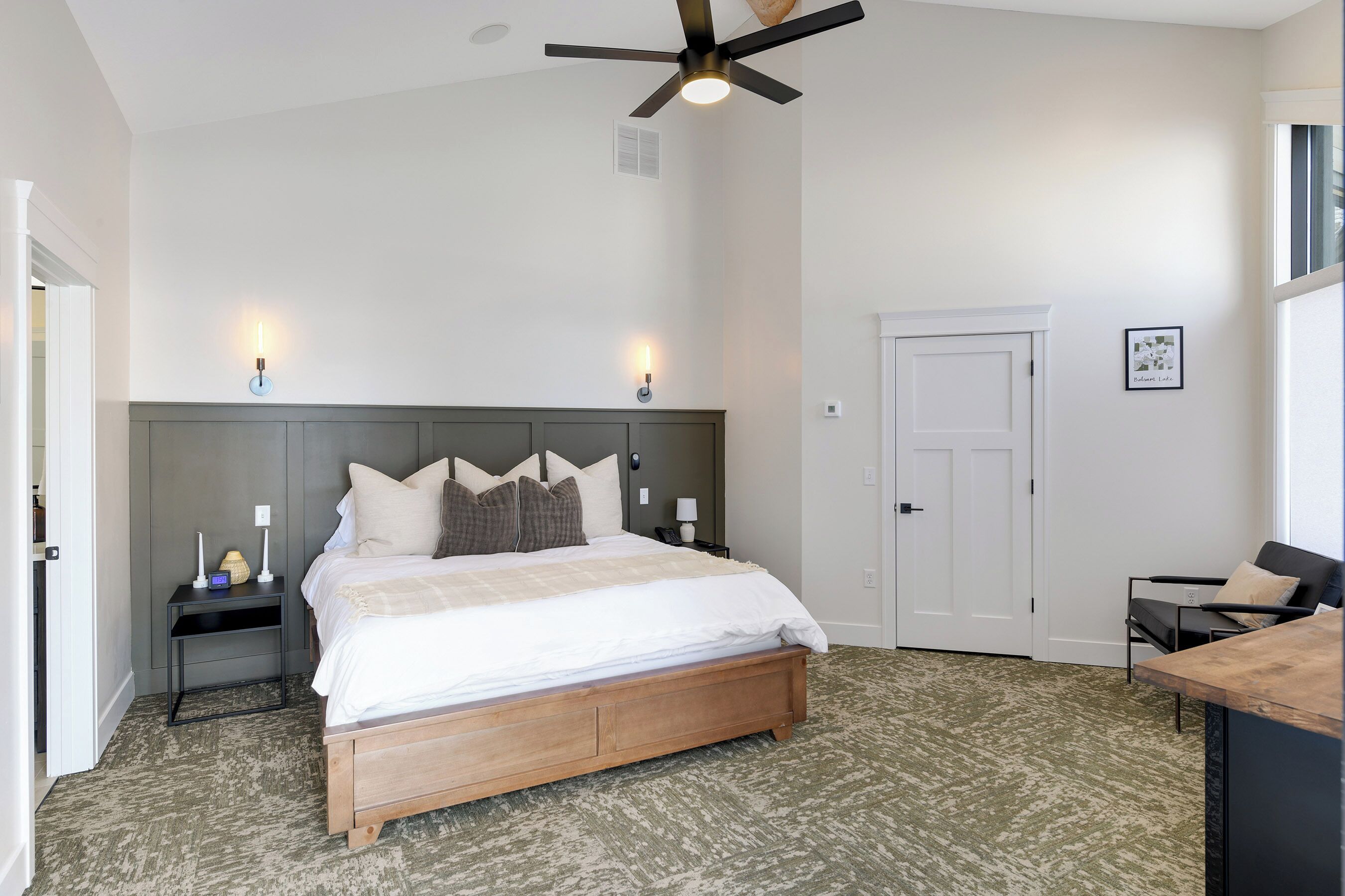 A bedroom with a bed, bedside tables, a ceiling fan, and a door.