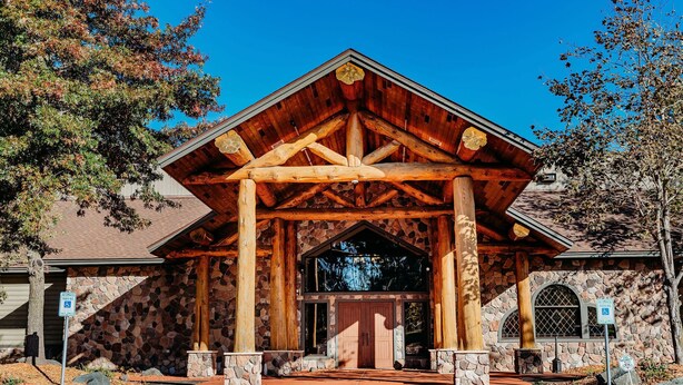A rustic lodge with a stone facade, wooden beams, and a covered entrance. - Balsam Lake Lodge (Balsam Lake)