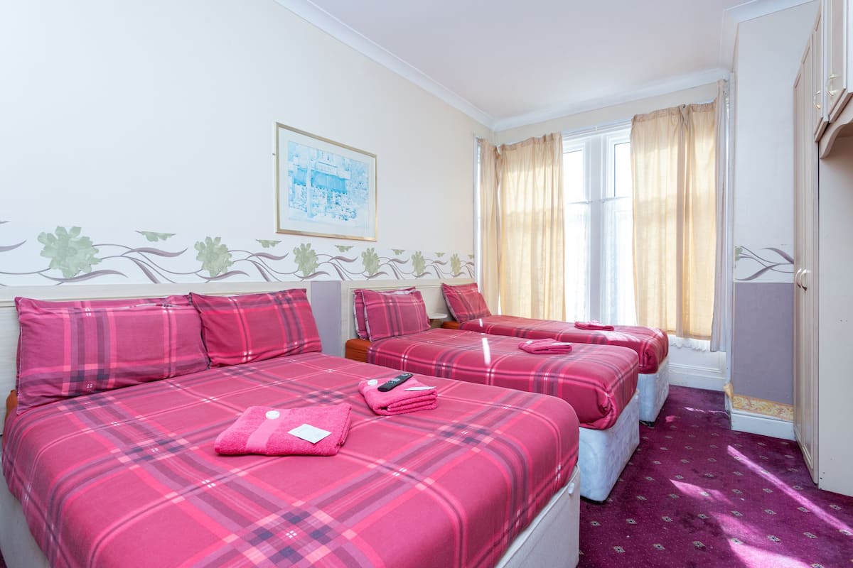 Habitación de hotel con dos camas, un cuadro en la pared y una ventana con cortinas.