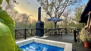 Una terraza exterior con una parrilla, mesas de picnic y una piscina.