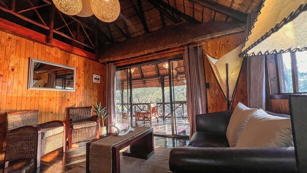 Un interior de madera con un sofá, sillas, una mesa y un ventanal grande.