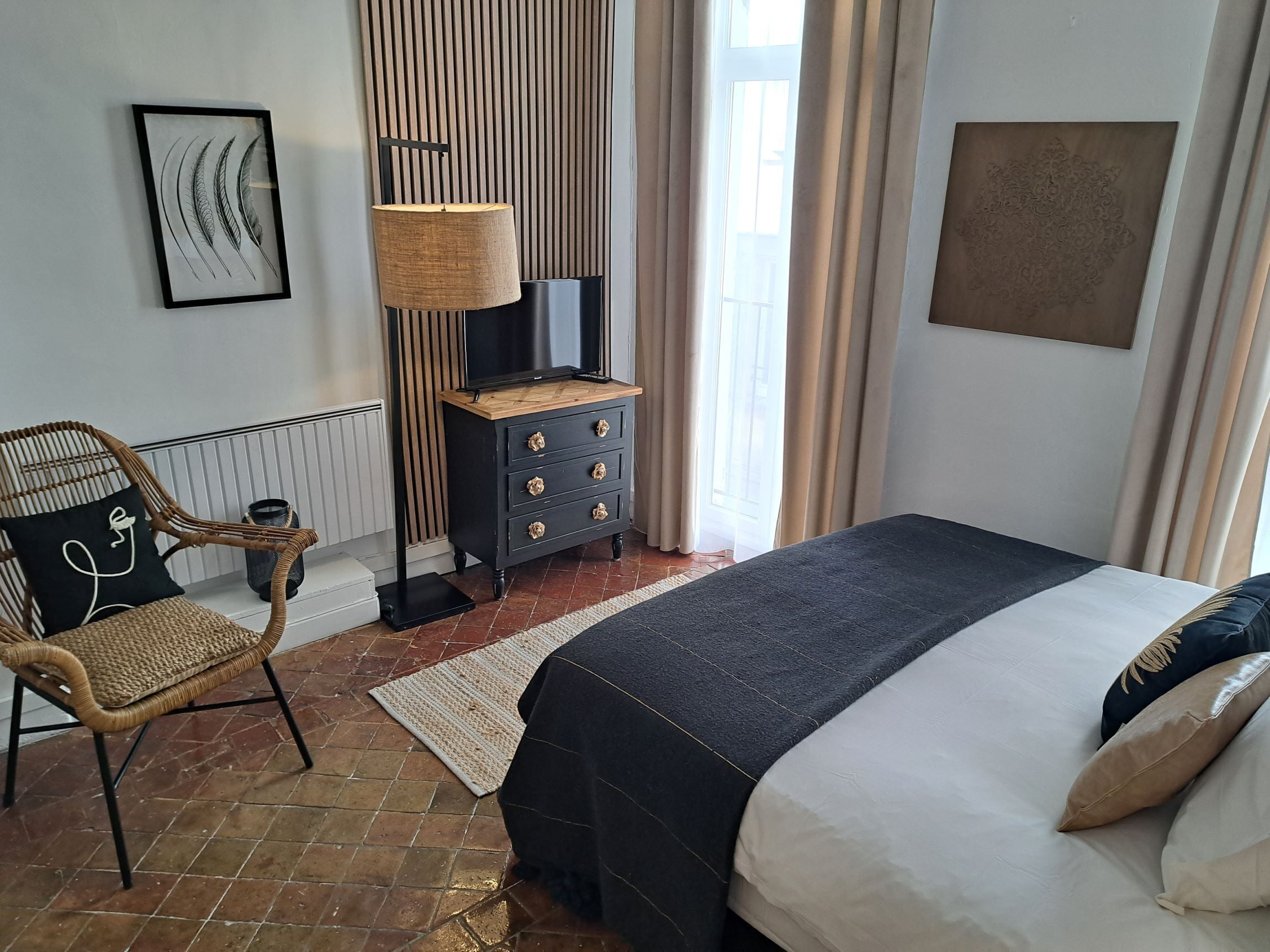 Una camera da letto ordinata con un letto, una sedia, una cassettiera, una lampada e un quadro appeso al muro.