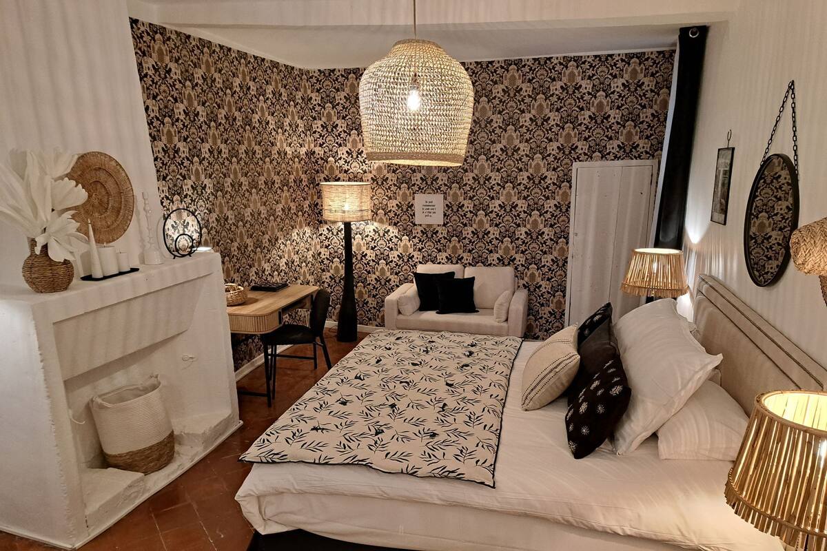 Un dormitorio con una cama, un escritorio, una silla, un sofá y una lámpara colgante.