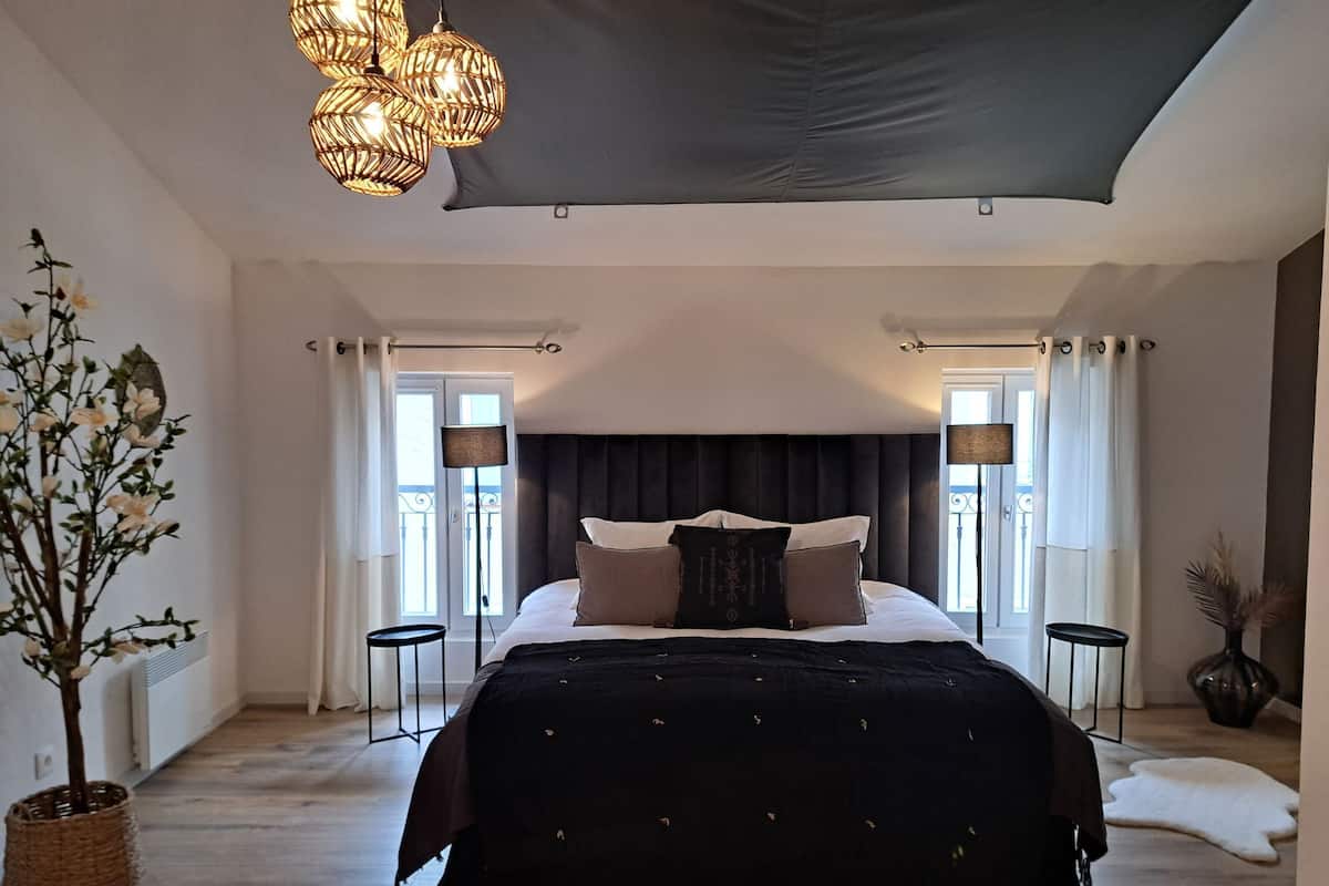 Un dormitorio con una cama grande, dos mesitas de noche, un techo oscuro y una planta en maceta.