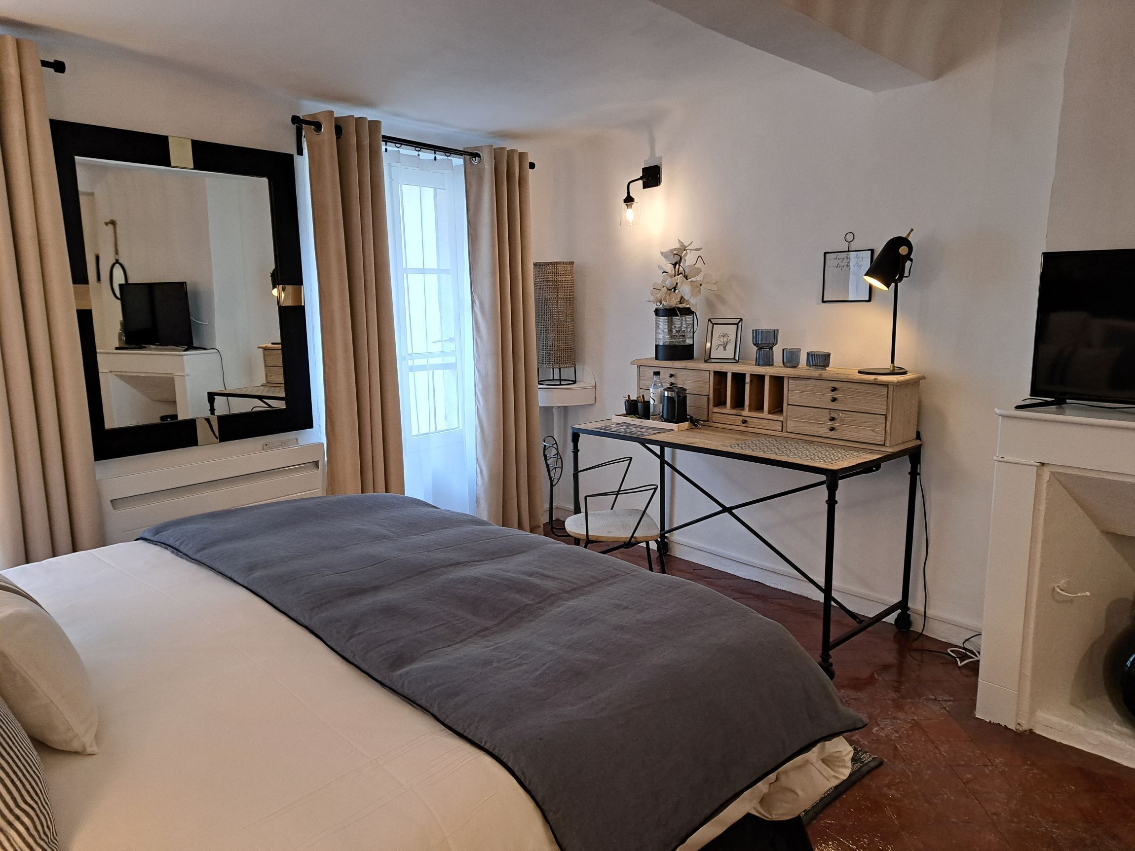 Un dormitorio con cama, escritorio, televisión y chimenea.