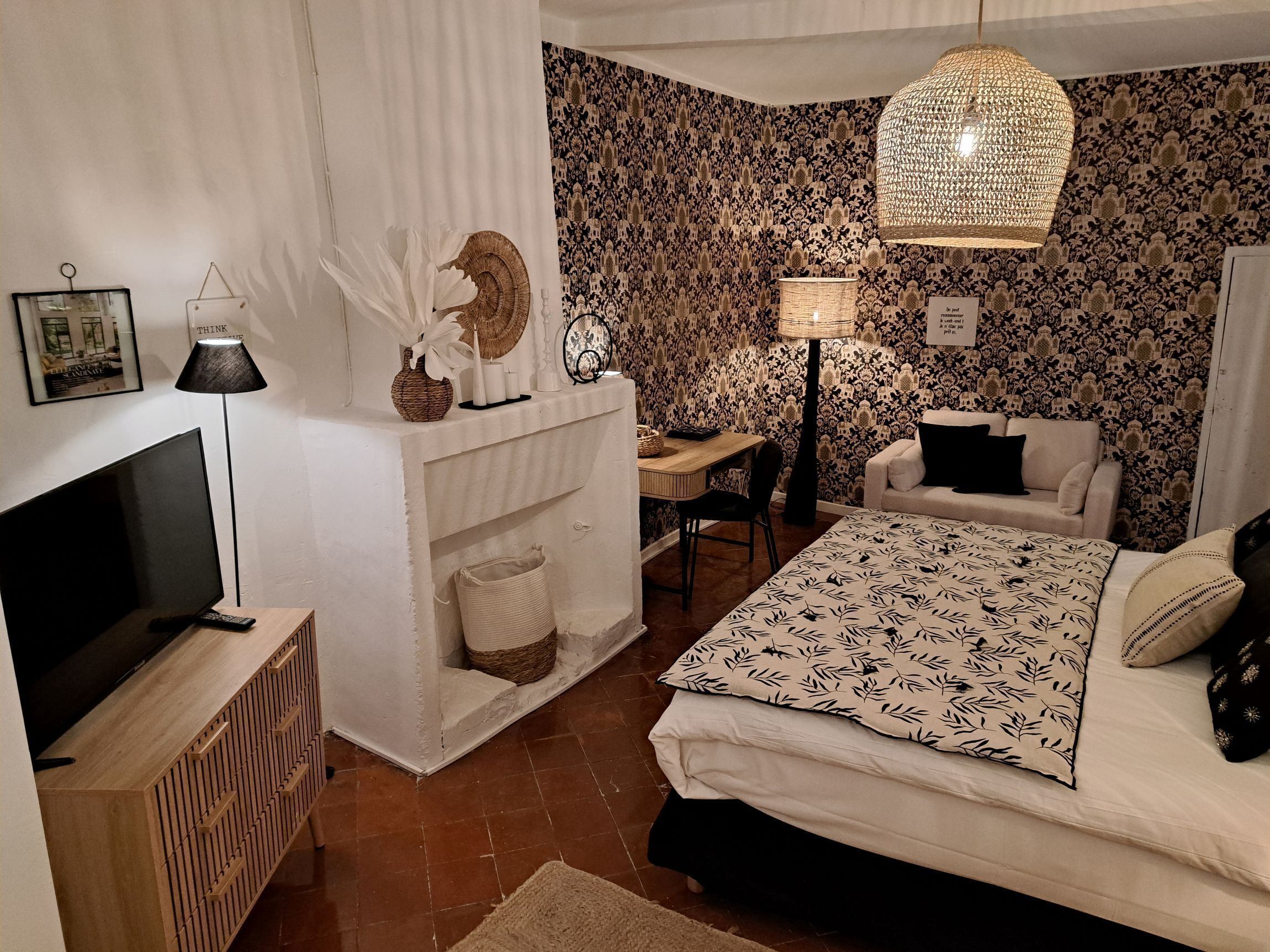 A bedroom with a bed, a desk, a chair, a TV, and a lamp.