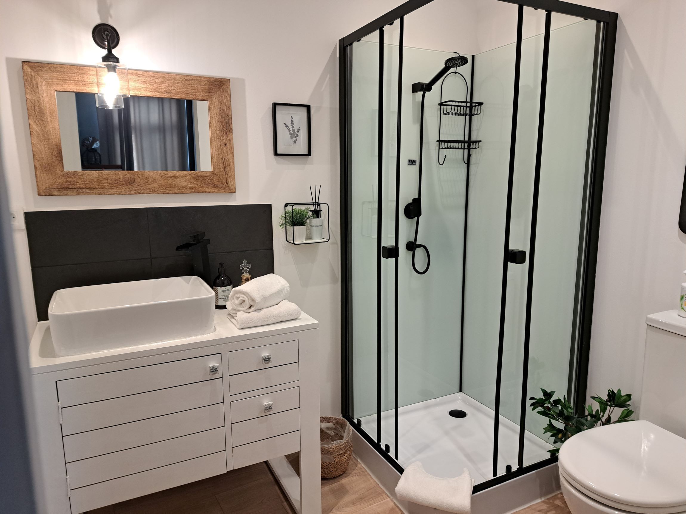 A modern bathroom with a glass-enclosed shower, a white sink, and a dark-toned vanity.