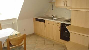 Eine kleine Küche mit Holzschränken, einem Geschirrspüler und einem Spülbecken.