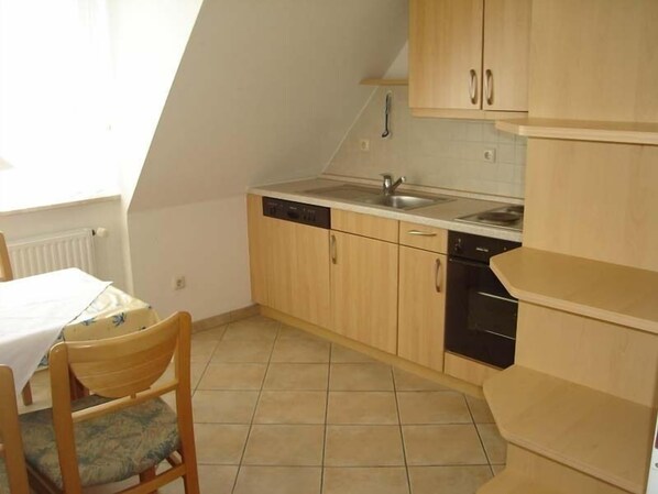 A small kitchen with wooden cabinets, a dishwasher, and a sink.
