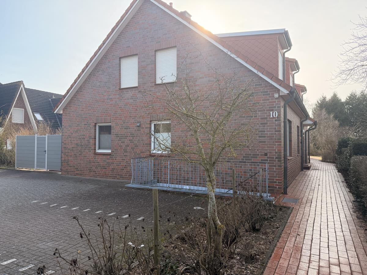 A brick building with a number '10' on the side, a gated driveway, and a paved pathway.