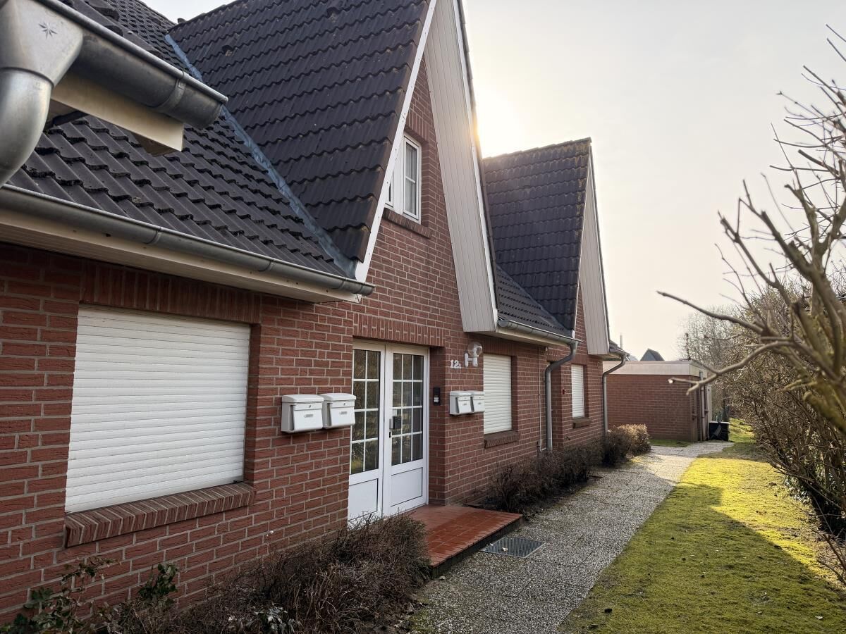 A residential building with a brick facade, a white garage door, and a gravel driveway.