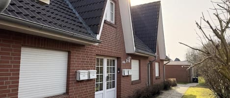 Ein Wohngebäude mit Backsteinfassade, einer weißen Garagentür und einem Schotterweg.