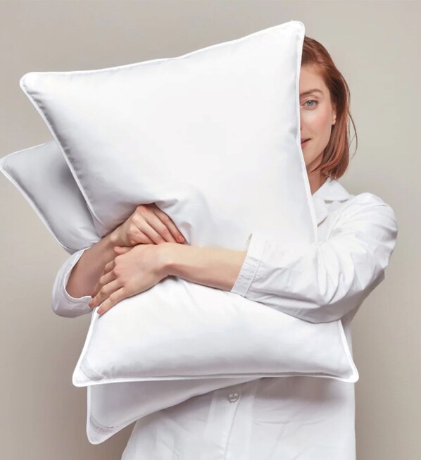 A person holding a large white pillow.