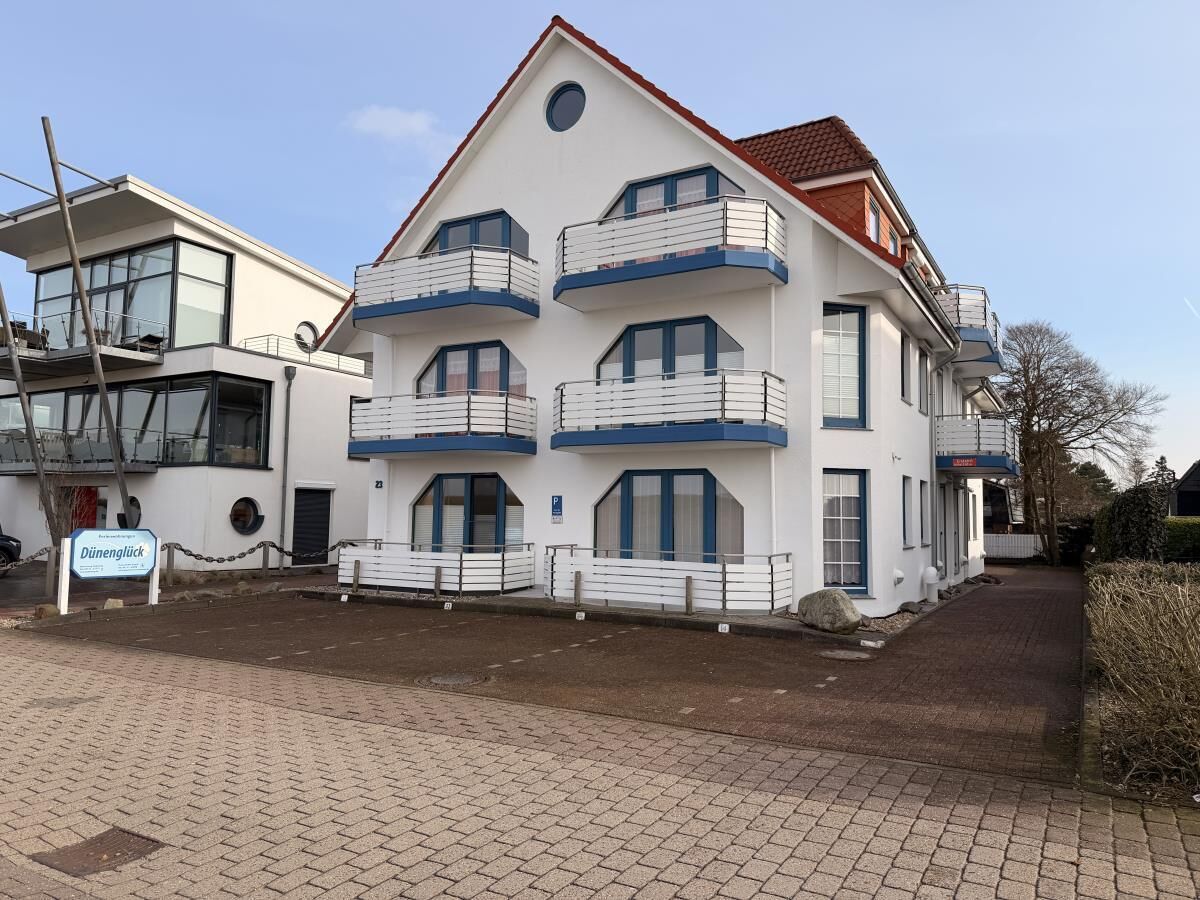 A white building with multiple balconies and a red roof.