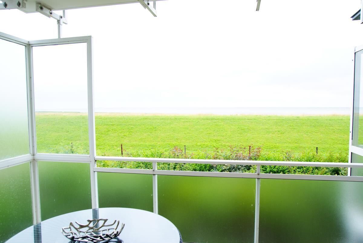 A room with a view of a green field through a large window.