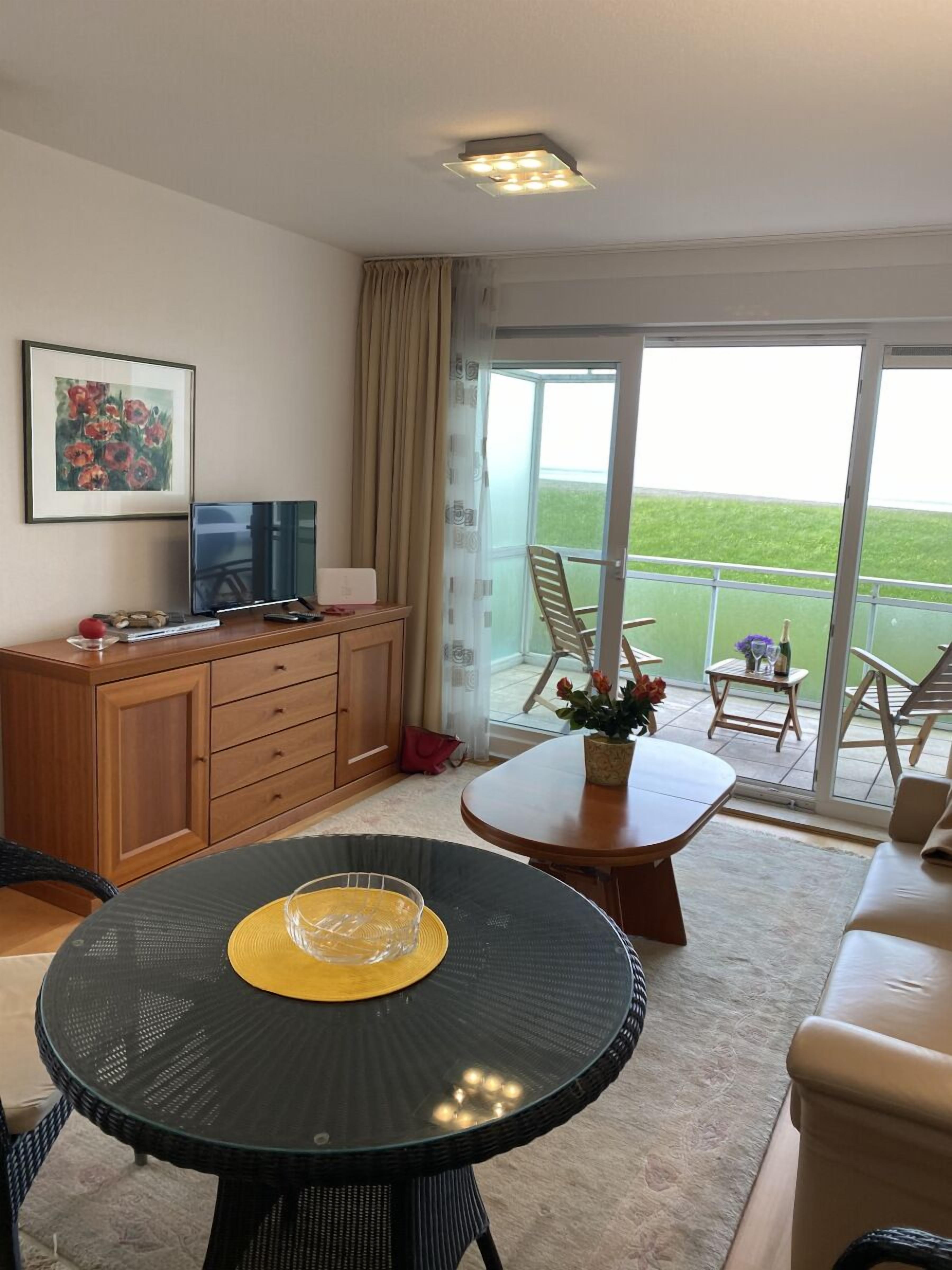 A living room with a TV, wooden cabinet, and a round table with a yellow placemat.