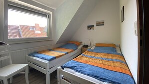 Ein Schlafsaalzimmer mit zwei Einzelbetten, einem Schreibtisch und einem Stuhl.