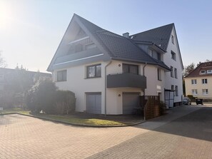 A two-story residential building with a sloped roof, a garage, and a paved driveway. - Haus Zyrus, Ferienwohnung 10 (Cuxhaven)