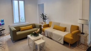 Ein modernes Wohnzimmer mit zwei Sofas, einem Couchtisch, einem Fernseher und einer Topfpflanze.