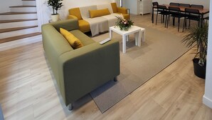 Ein Wohnzimmer mit einem grünen Sofa, einem weißen Couchtisch und einem Essbereich mit einem Holztisch und Stühlen.