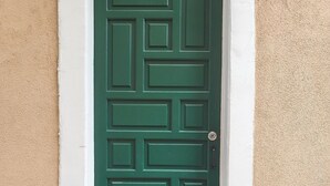 Eine grüne Tür mit geometrischem Muster, beiderseits von zwei Steinfiguren flankiert.