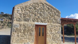 A small stone church with a bell tower and a wooden door. - Irini's Home Pitsidia 
Family friendly (Πιτσίδια)