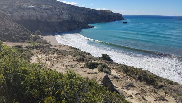 A coastal landscape with a beach, rocky cliffs, and a clear blue sky. - Irini's Home Pitsidia 
Family friendly (Πιτσίδια)