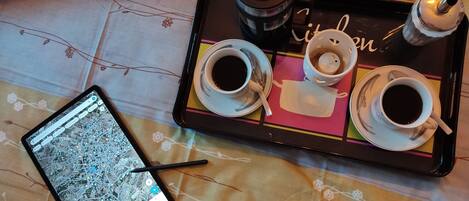 A tray with three cups of coffee, a teapot, and a smartphone displaying a map.