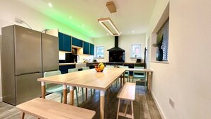 A modern kitchen with a central island, wooden benches, and a dining table. - Massive New House Sleeps 20+ Accepts Groups (Bournemouth)