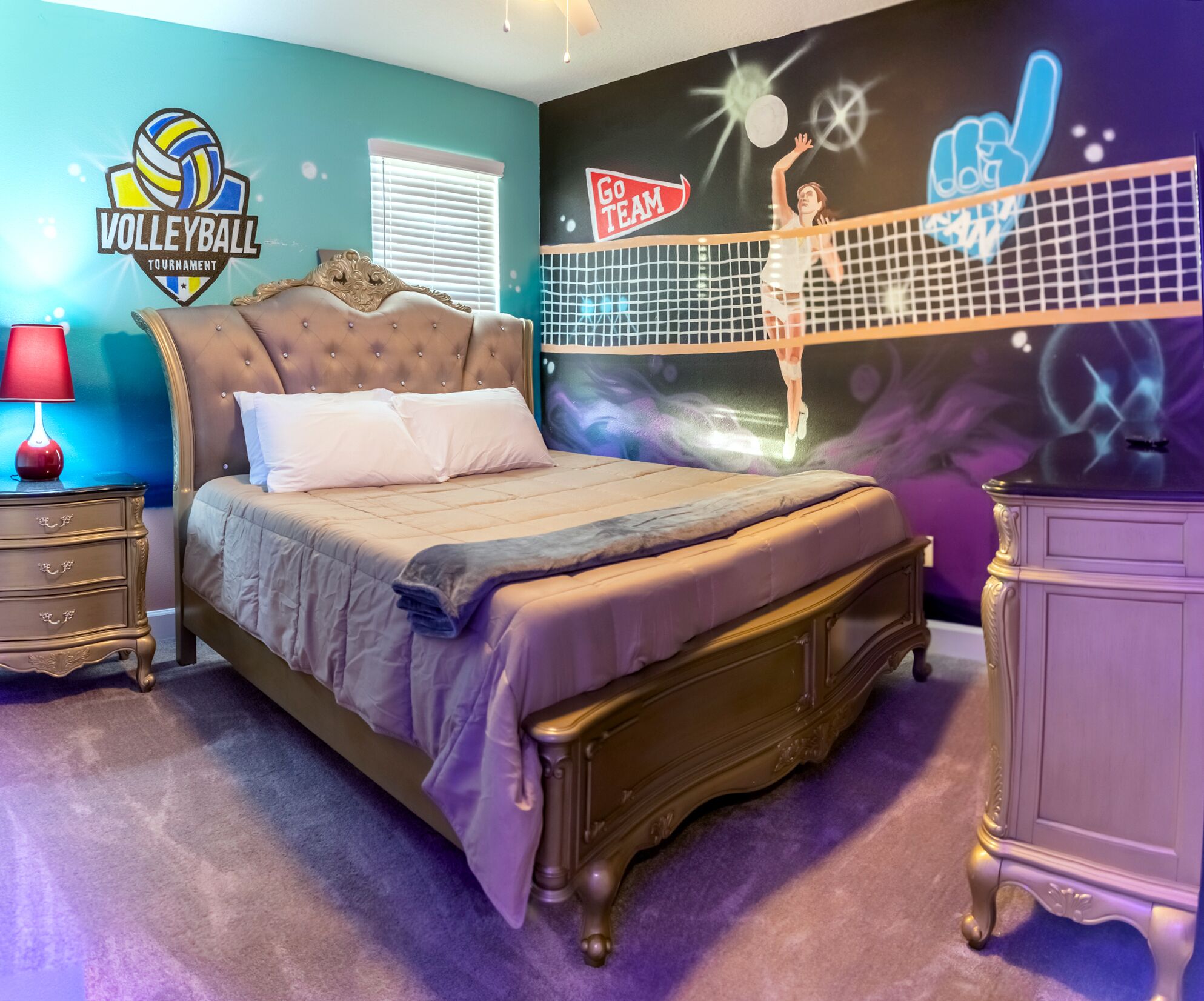 Quarto com uma cama grande, mesa de cabeceira, cômoda e um mural na parede.