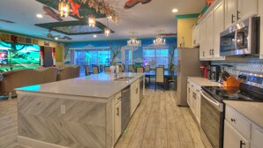 A modern kitchen with a large island, white cabinets, stainless steel appliances, and decorative ceiling art. - 2 Side-by-side homes w Bowling, 1GB wifi, videowall TVs, ensuites, sleep 80 (Kissimmee)