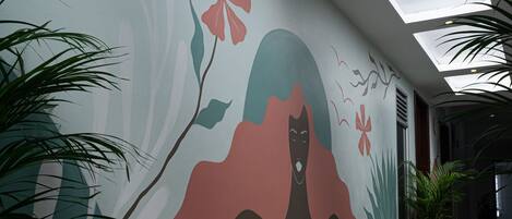 Un interior moderno con un mural, tragaluces y plantas en macetas.