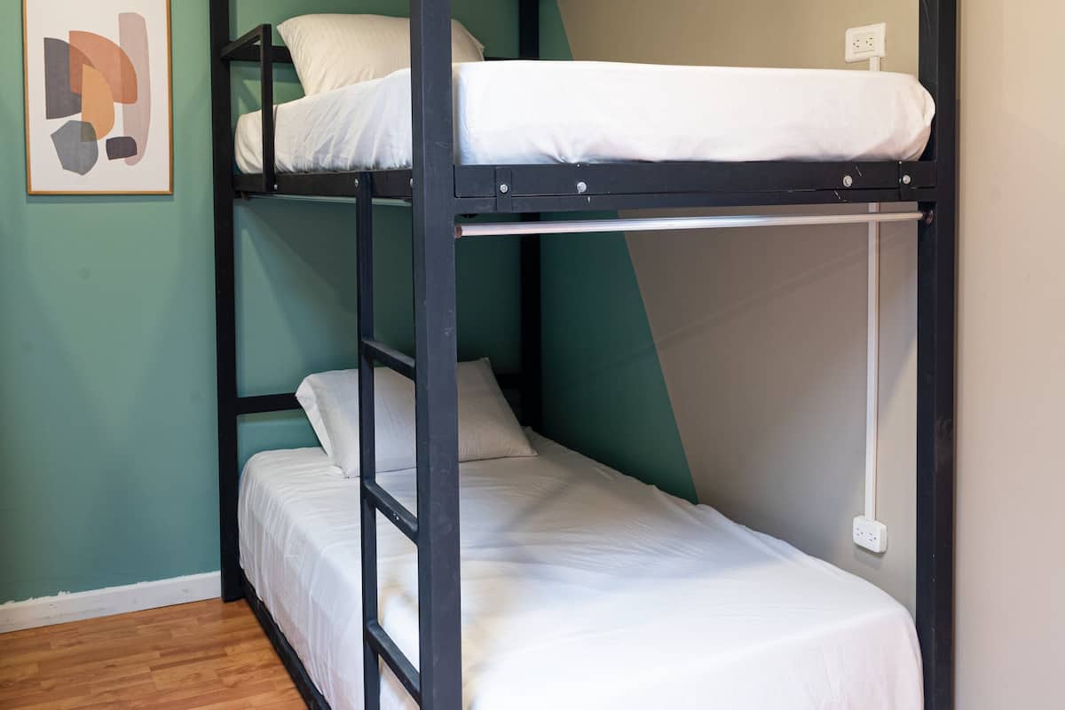 A bunk bed with two levels, a framed picture on the wall, and a wooden floor.