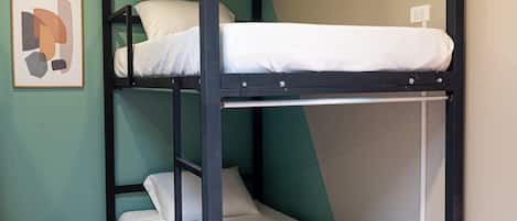 Una cama litera de dos niveles, un cuadro en la pared y un piso de madera.