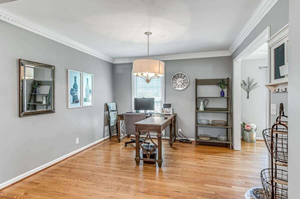 A spacious room with hardwood flooring, a dining table, a computer desk, and a bookshelf.