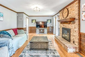 Una sala de estar con sofá, mesa de centro, chimenea y televisor.