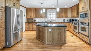 Una cocina moderna con armarios de madera, electrodomésticos de acero inoxidable y una isla central.