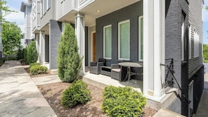 Ein modernes Reihenhaus mit überdachter Terrasse, kleinem Garten und Ziegel-Fassade.