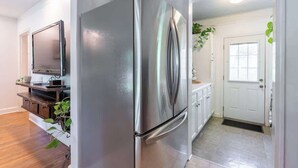Eine moderne Küche mit einem Edelstahl-Kühlschrank, Holzschränken und einem flachbildfernseher an der Wand.
