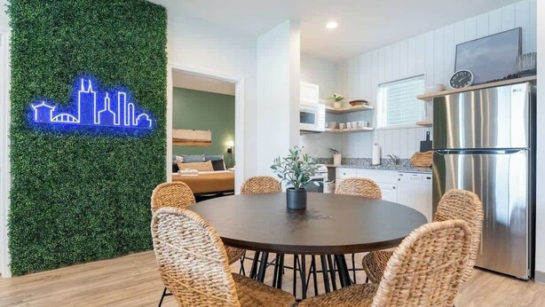 Una cocina moderna con un refrigerador de acero inoxidable y un comedor con sillas de mimbre y una mesa redonda.