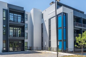A modern multi-story building with balconies, large windows, and a blue accent wall.
