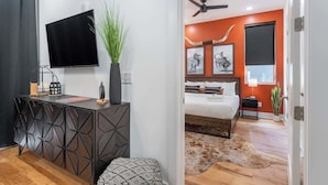 A modern bedroom with a bed, a TV, and a ceiling fan.