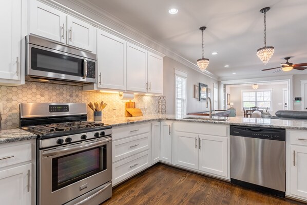 Kitchen features a large island with a sink, stainless steel appliances, and pendant lights.