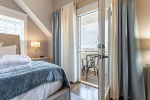 Relax in this serene space with a large bed, bedside table, and glass door leading to an outdoor area with a chair and table.