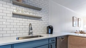 Une cuisine moderne avec des carreaux de céramique blancs disposés en motif métro, un évier à deux bacs et des armoires bleues.