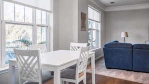 A dining area with a white table and chairs, a blue sofa, and a patterned ceiling light. - The Elliot - Pool & Gym Amenities (Nashville)