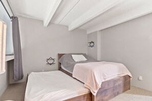 A bedroom with a bed, a bedside table, a wall-mounted light fixture, and a window with a curtain. - Dog Friendly, Spacious Condo, Great Views, Large Deck, East Village, WH405 (Copper Mountain)